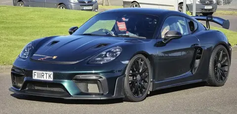 A 2022 Porsche 718 Cayman GT4 RS in a wide three-quarter shot, with its GT3-derived engine breathing through the rear glass louvres.