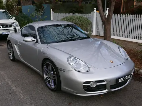 A 2006 Porsche Cayman S (987) coupe photographed outdoors, from the launch year when Porsche marked the naming with a marketing stunt at Stuttgarts Wilhelma Zoo.