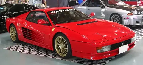A Ferrari Testarossa in side profile, showing the horizontal side strakes fitted to comply with European pedestrian-safety rules.