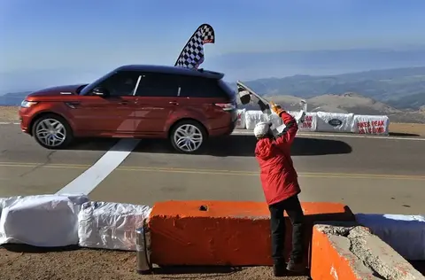 The record-setting Range Rover Sport crossing the finish line at the Pikes Peak Hill Climb as an official waves the checkered flag.