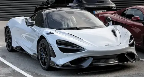 A McLaren 765LT on display outdoors, front three-quarter view showing its carbon front splitter.