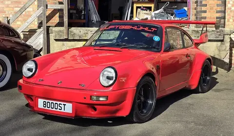 A silver 1985 Porsche 911 Carrera 3.2 photographed outdoors in front three-quarter view.