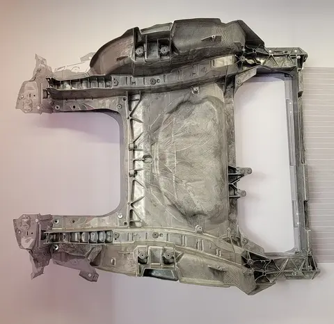 A close-up section of a Tesla gigacast aluminium frame component, showing the single-piece casting process.