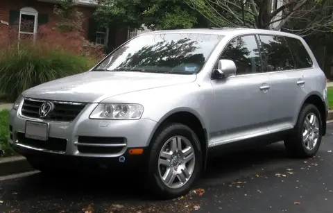 Silver first-generation Volkswagen Touareg parked on a suburban street, front three-quarter view.